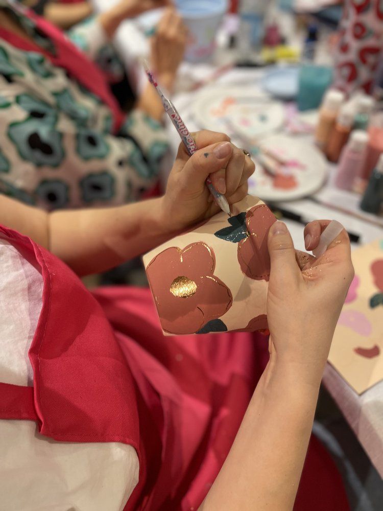 Manos con un pincel pintando una maceta de cerámica