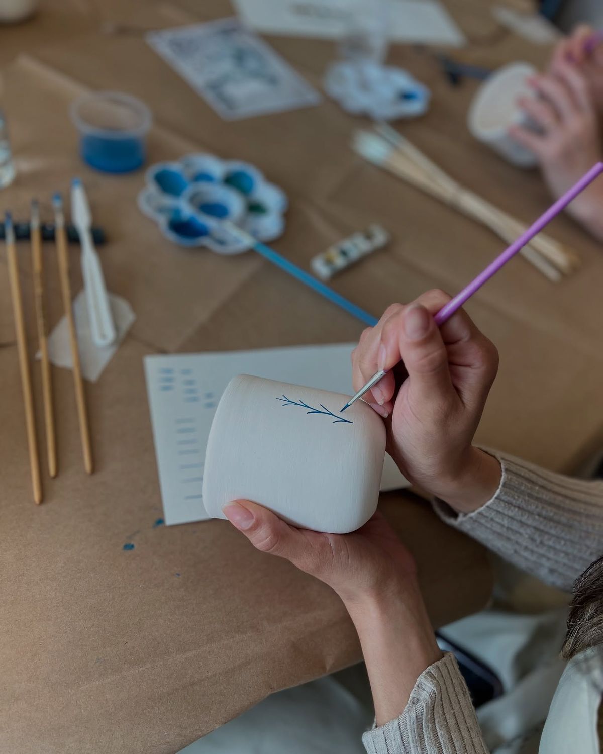 Manos de chica pintando taza